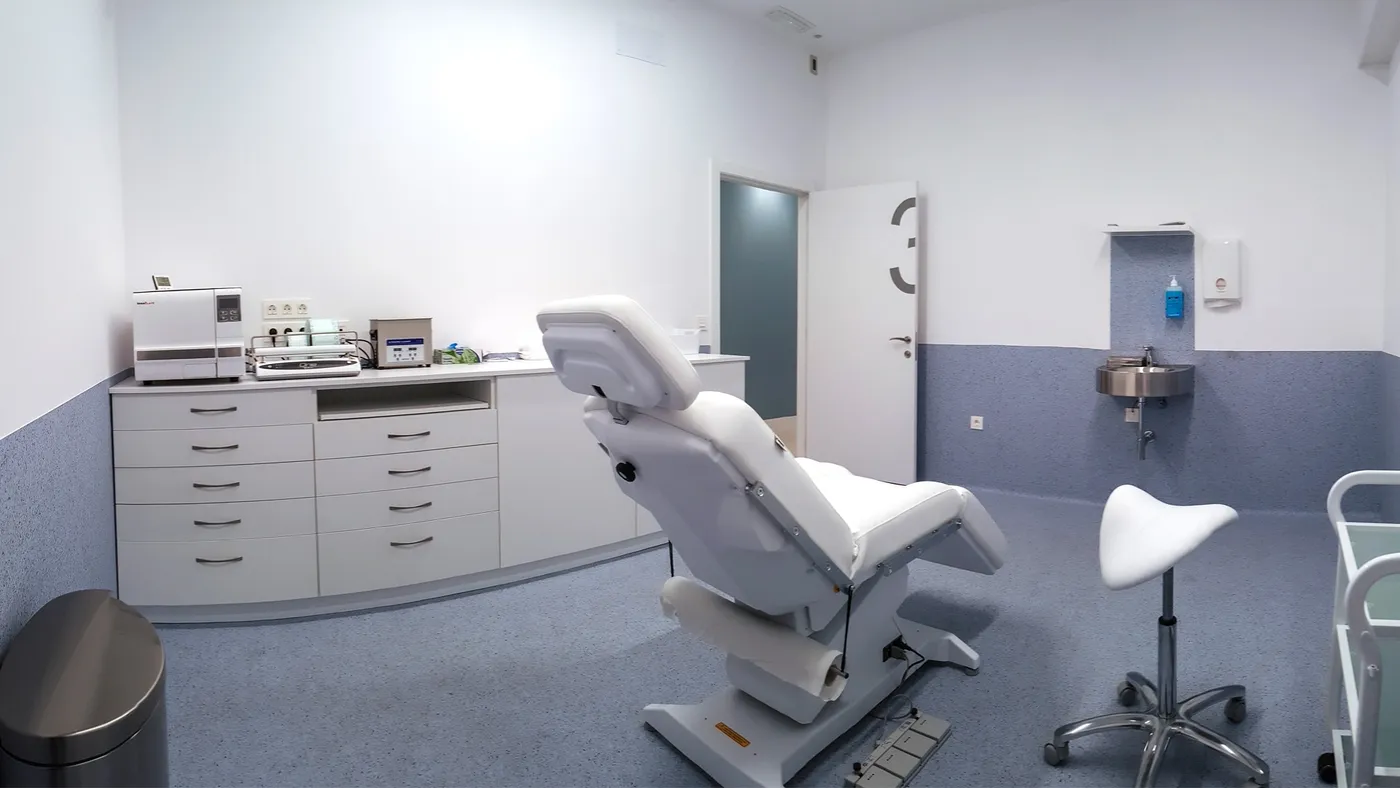 Sala de tratamiento con sillón clínico reclinable, lavabo y equipamiento auxiliar